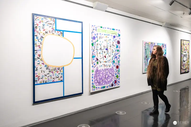 Visitor Exploring Abstract Artworks at Strabag Kunstforum's "Storyteller" Exhibition