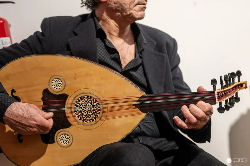 Traditional Oud Player Performing in Black Jacket at Cultural Event