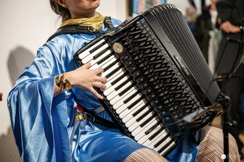 Blue-Robed Accordionist Performing at "Lebensquelle Wasser" Exhibition Vernissage