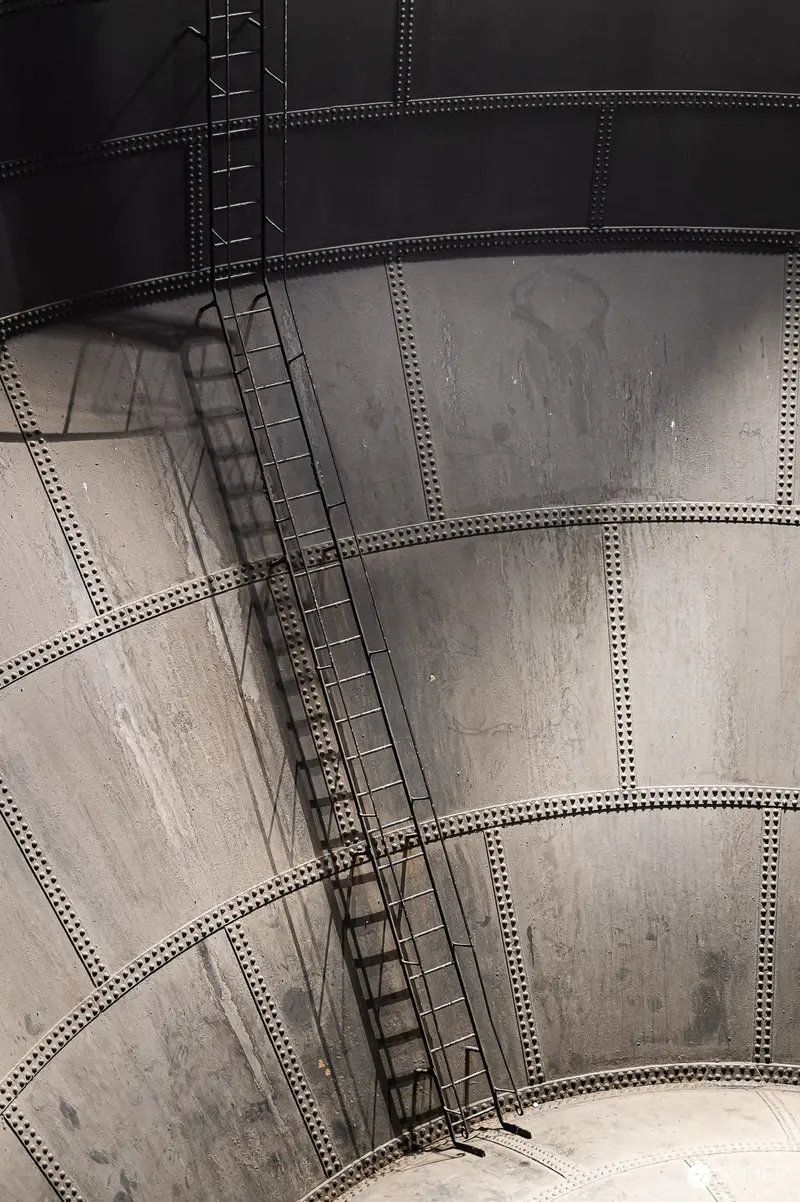 Industrial Water Tower Ladder Against Riveted Metal Storage Tank