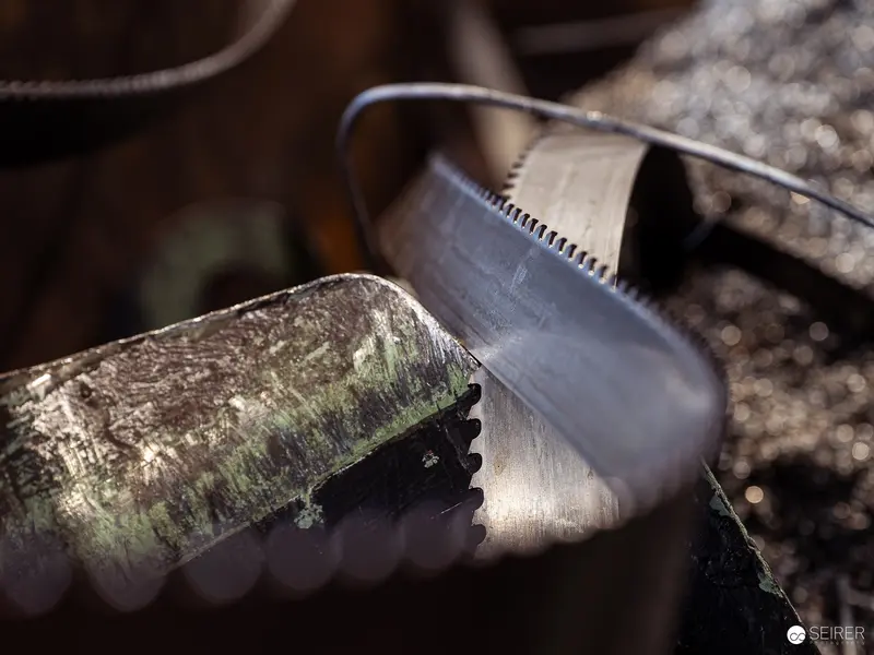 Rusty Saw Blade Cutting Through Metal Log in Workshop Setting