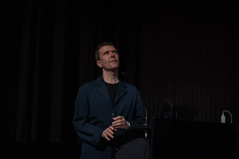Speaker at 60th Anniversary Event of Filmmuseum in Dark Stage Setting