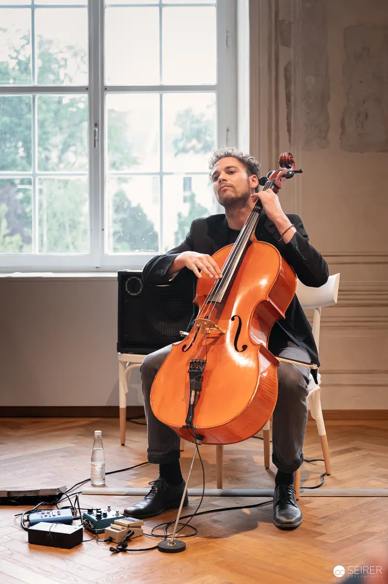Cellist Performing with Electronic Setup in Minimalist Studio Setting