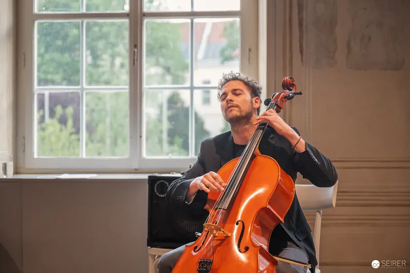 Cellist Performing Passionately in Elegant Interior with Large Windows