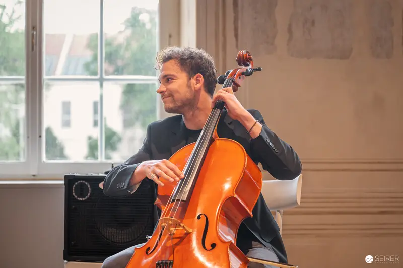 Cellist in Black Jacket Performing by Window at Vienna Event