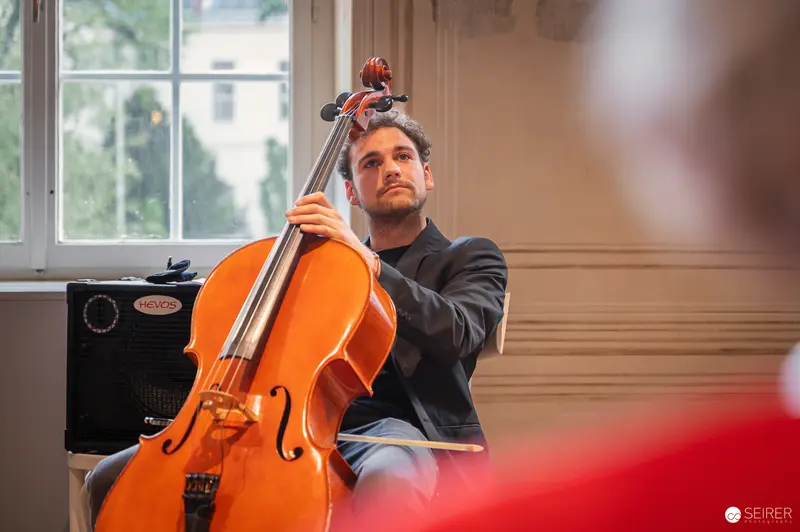 Cellist in Contemplative Pose During Book Presentation at Josephinum