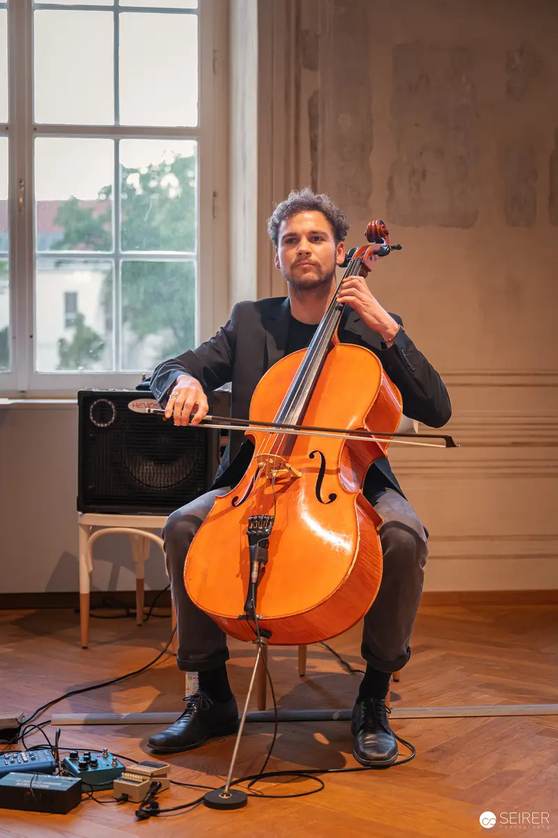 Professional Cellist Performing with Electronic Equipment Near Window