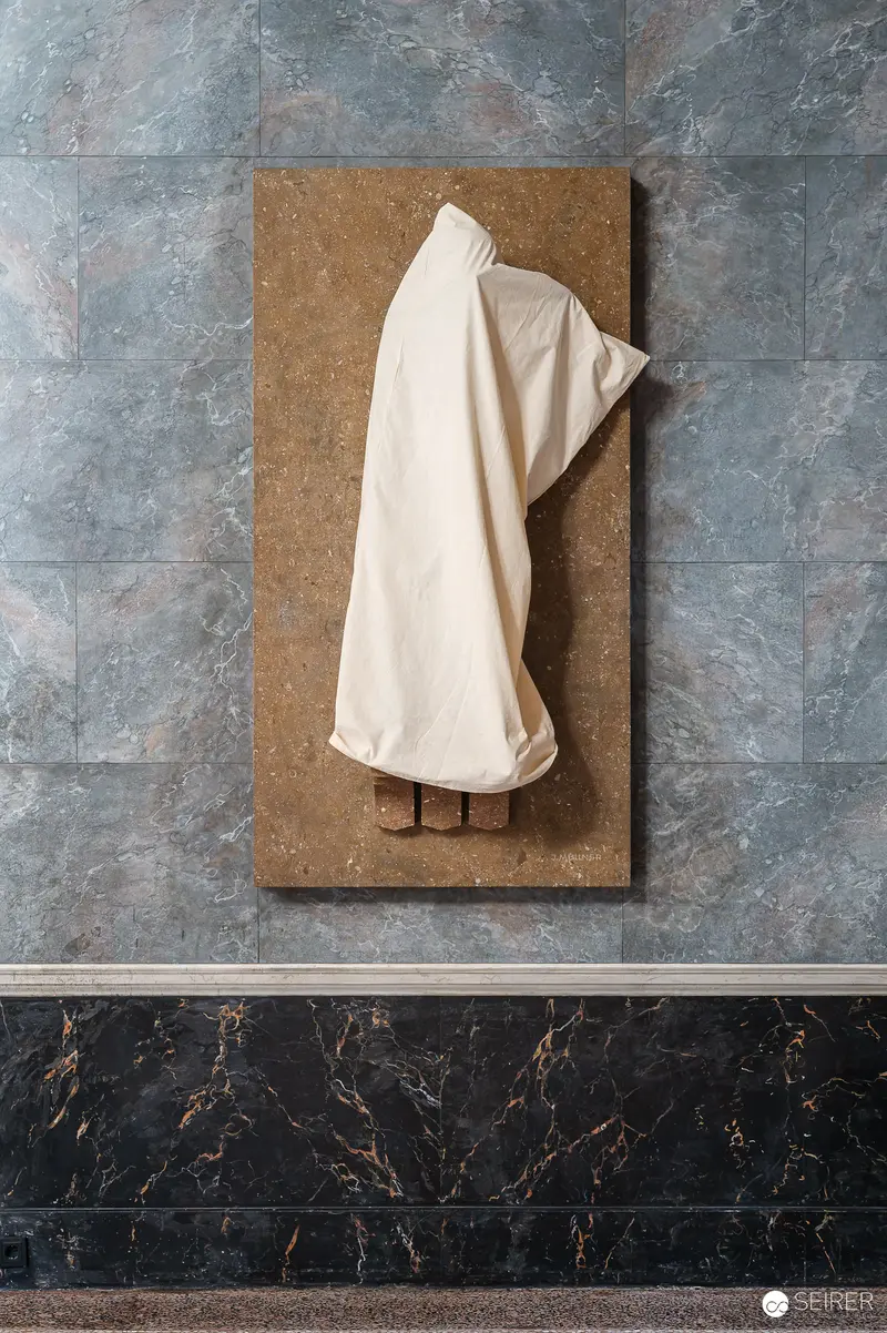 Draped White Garment on Brown Panel Against Marble Wall