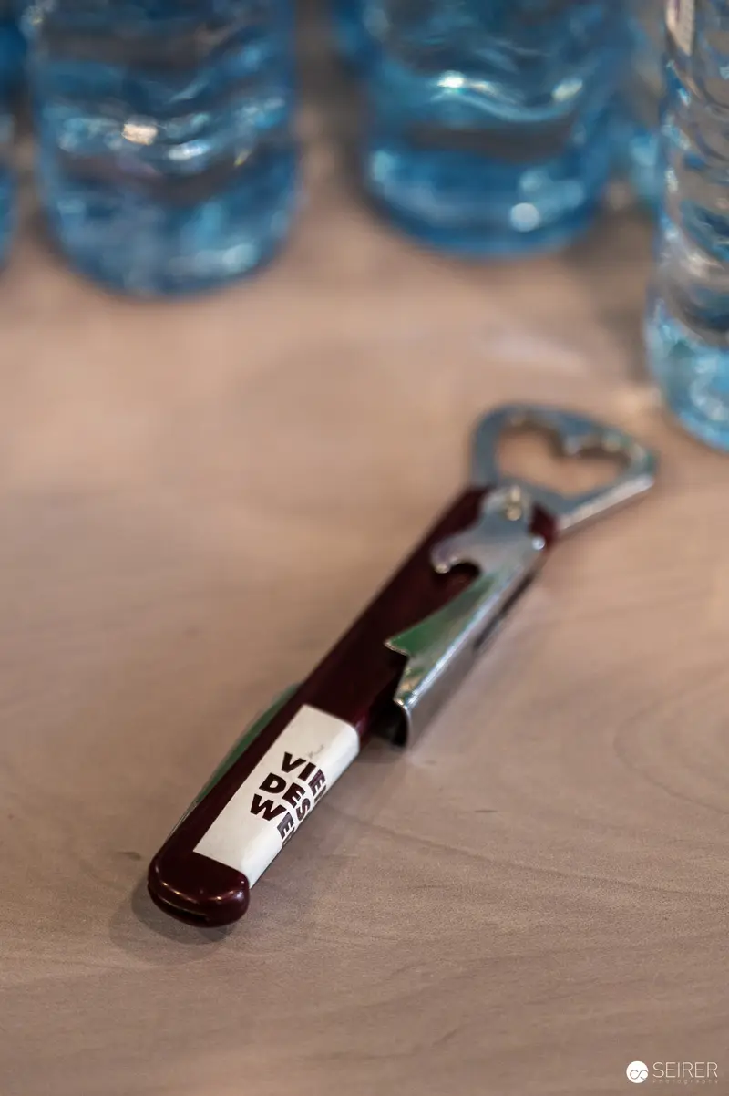 Dark Bottle Opener with White Label on Wooden Surface