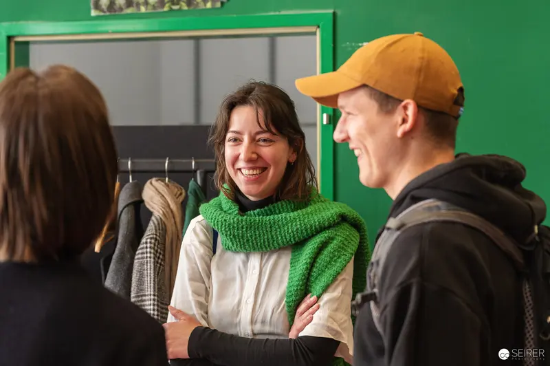 Three People in Conversation at Press Preview Event with Green Interior