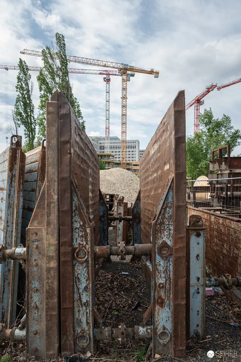 Construction Site Excavation with Rusted Steel Walls and Overhead Cranes