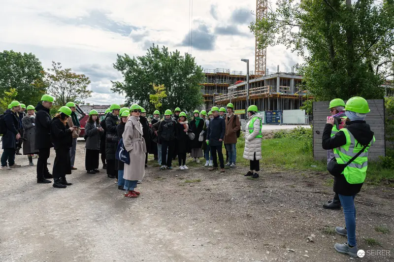Construction Site Tour with Safety-Helmeted Visitors and Building Under Development