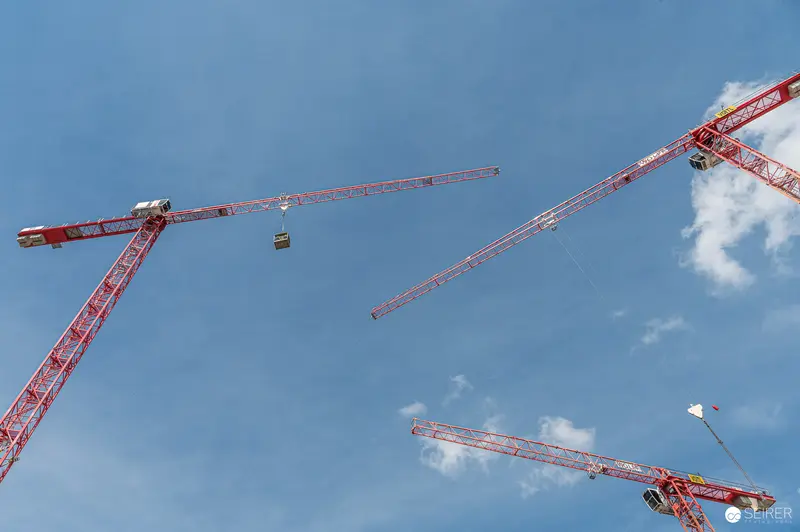 Multiple Red Tower Cranes Against Blue Sky at Construction Site
