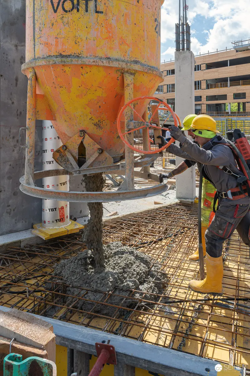 Construction Worker Operating Concrete Pump on High-Rise Building Site