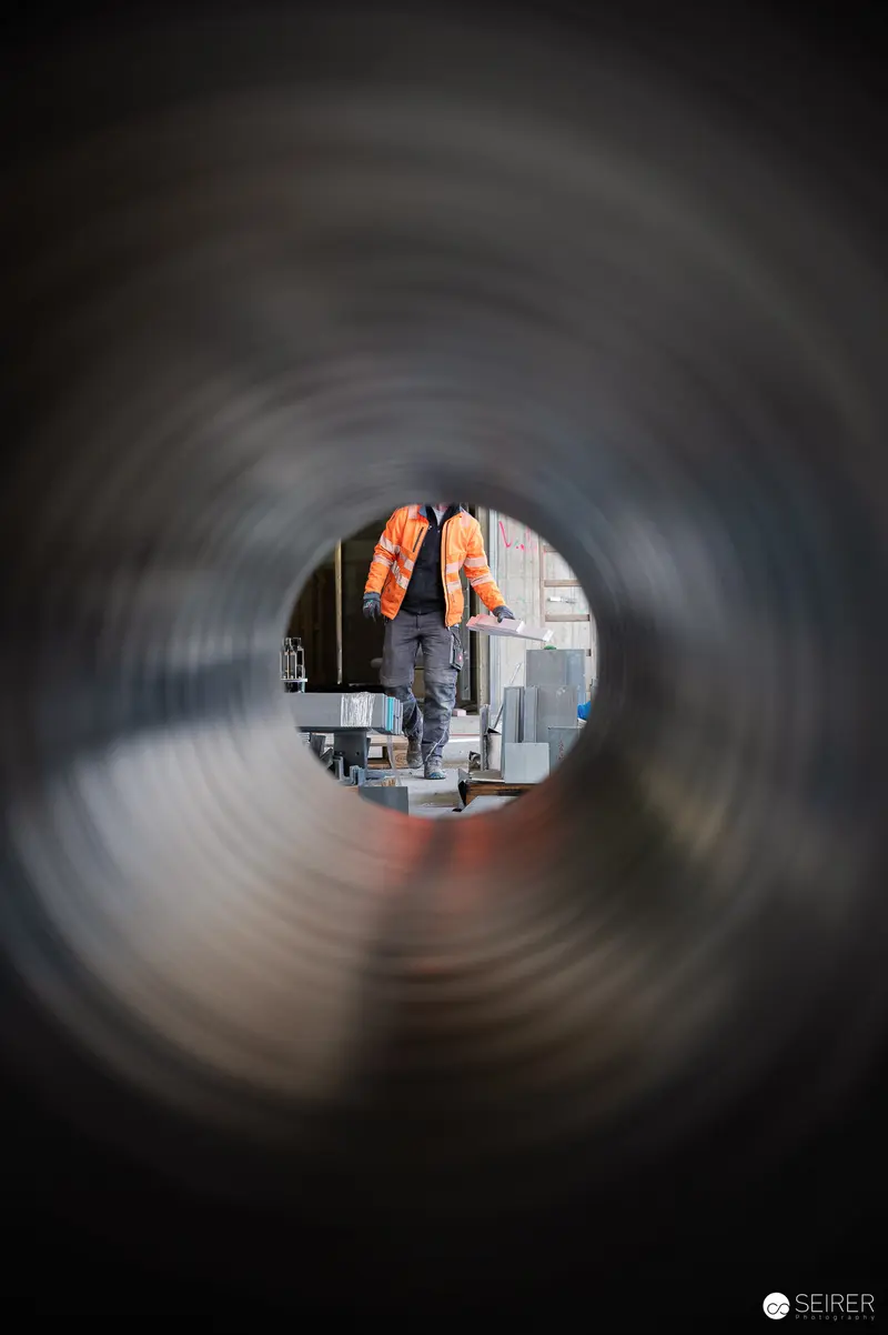 Construction Workers in Safety Vests Viewed Through Concrete Pipe