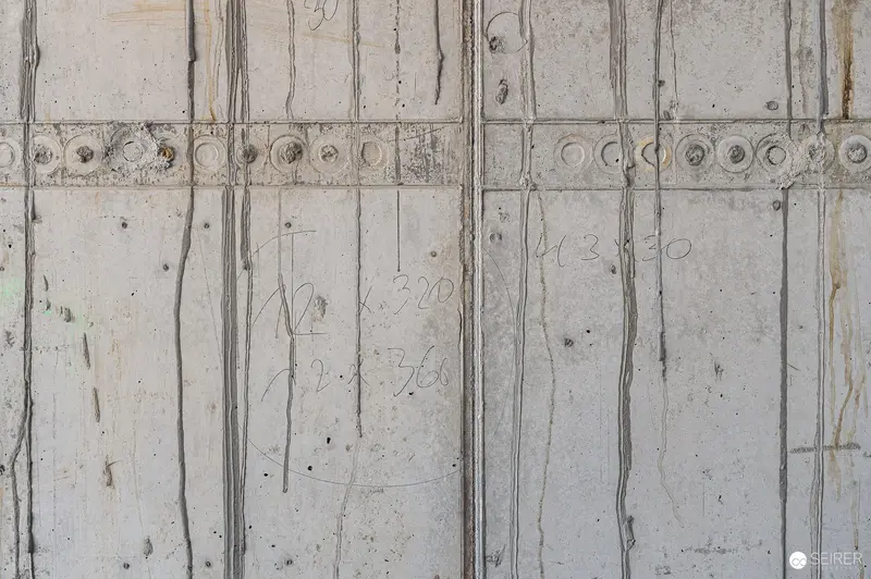 Raw Concrete Facade with Vertical Panel Joints and Decorative Circular Band