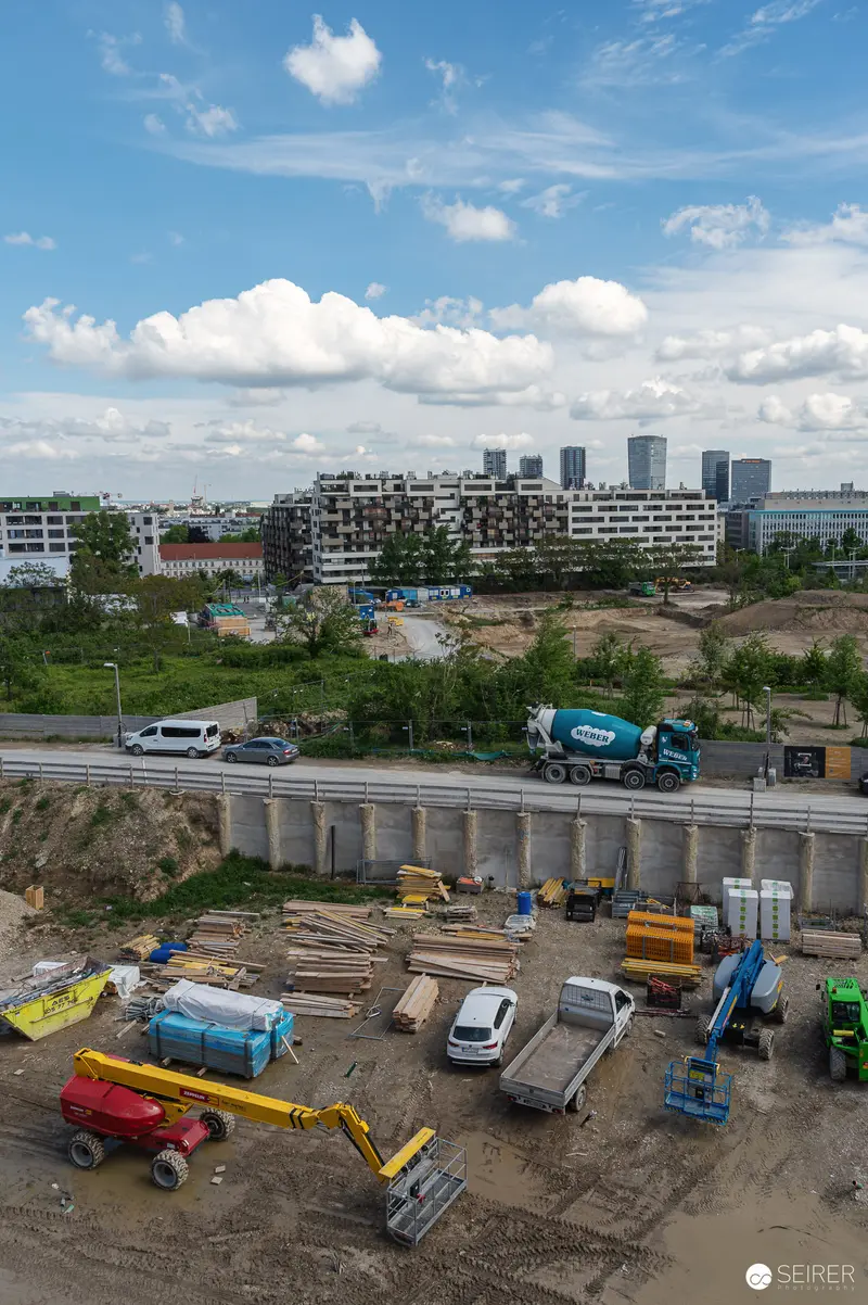Aerial View of Urban Construction Site with Heavy Machinery and Highway Overpass