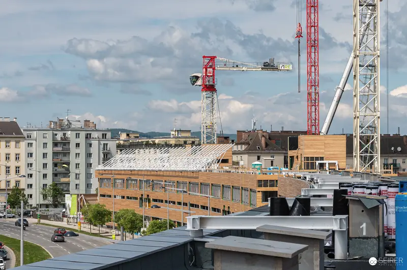 Multi-Story Construction Site with Tower Cranes and Wooden Facades