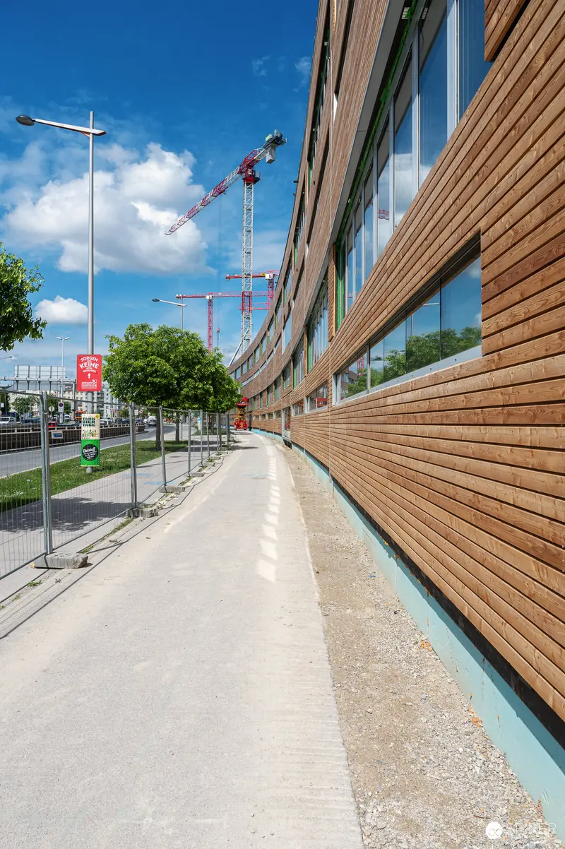 Modern Wooden-Clad Building Along Concrete Walkway During Construction Phase