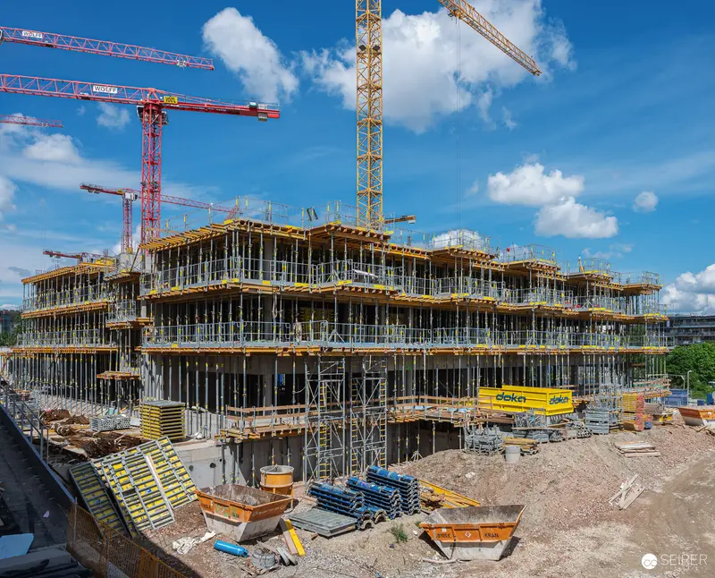 Multi-Story Building Under Construction with Tower Cranes and Yellow Formwork Systems