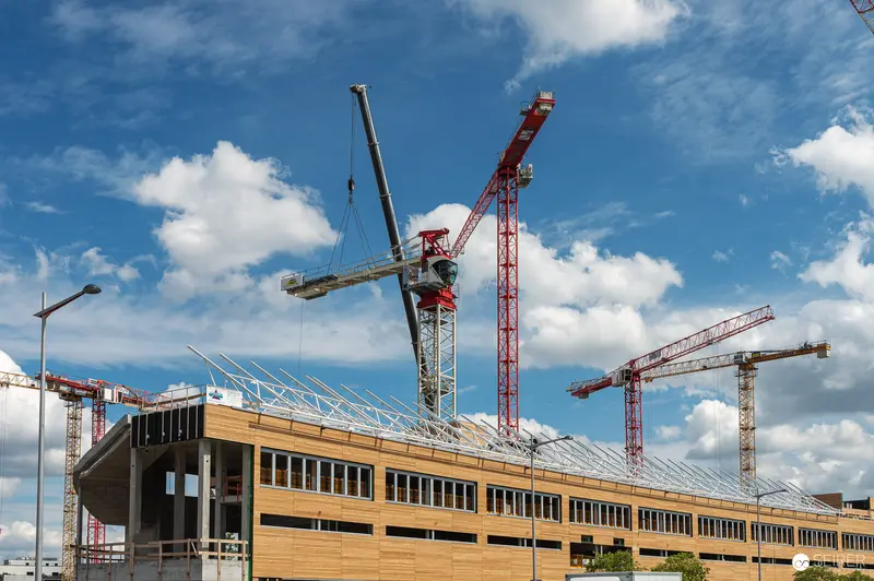 Large-Scale Construction Site with Tower Cranes and Wooden-Framed Building Structure