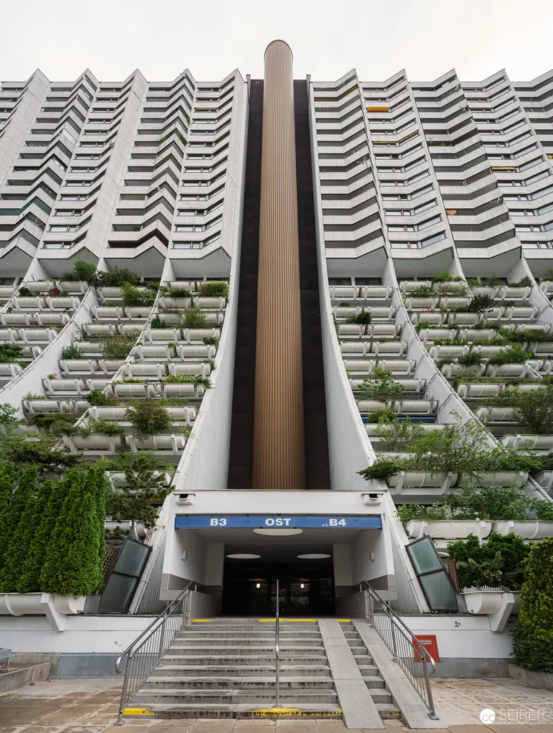 Modernist Urban Housing Complex with Green Terraced Facade and Central Entrance