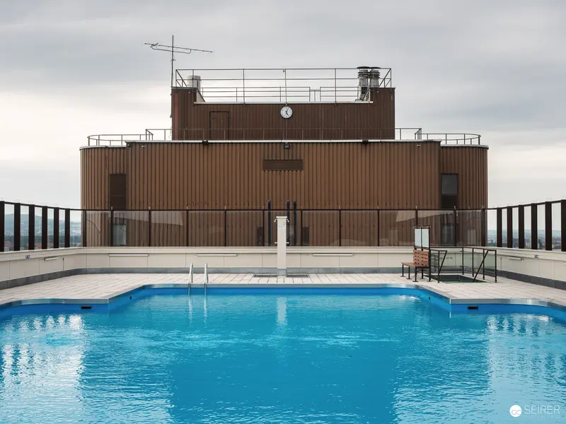 Rooftop Swimming Pool with Brown Building and Cloudy Sky