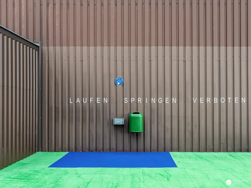 Minimalist Urban Sign Installation Displaying Restriction Text on Corrugated Wall