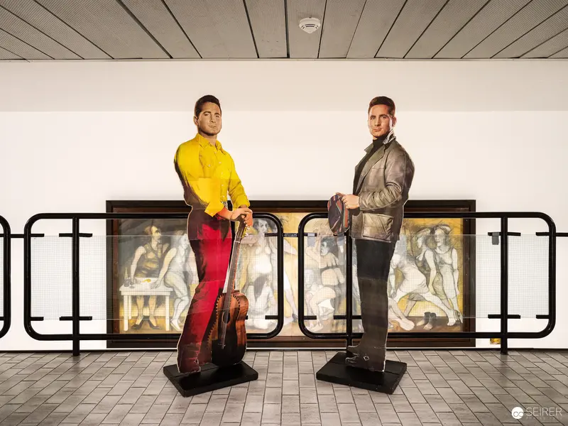 Two Figures in Yellow and Red at Architectural Exhibition Display