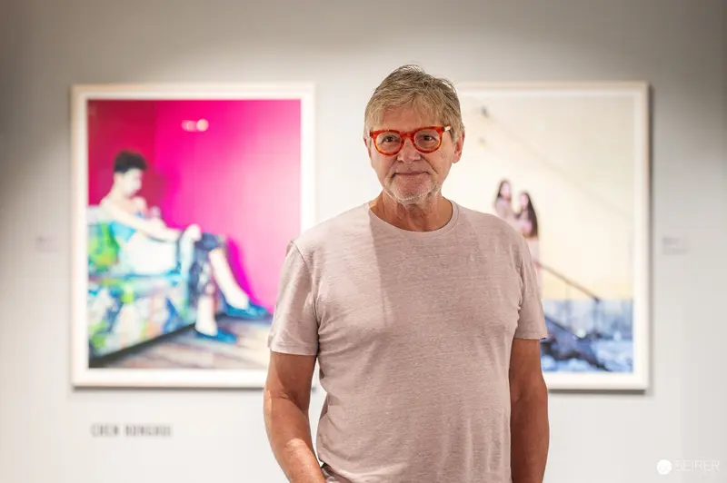 Senior Artist Standing Before Vibrant Gallery Artwork at Exhibition Opening