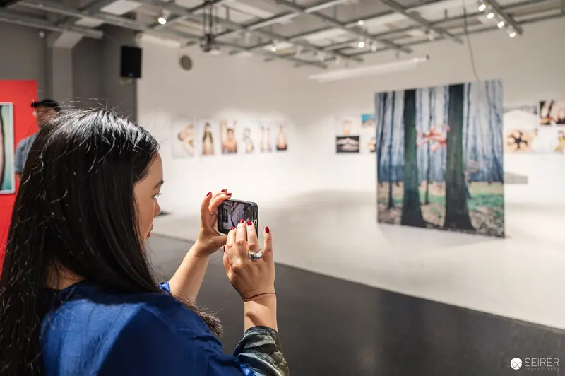 Visitor Photographing Forest Landscape at Art Gallery Exhibition