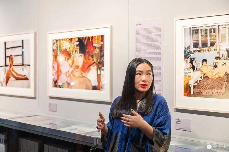 Woman in Blue Discussing Artwork at Gallery Exhibition of Contemporary Photographs