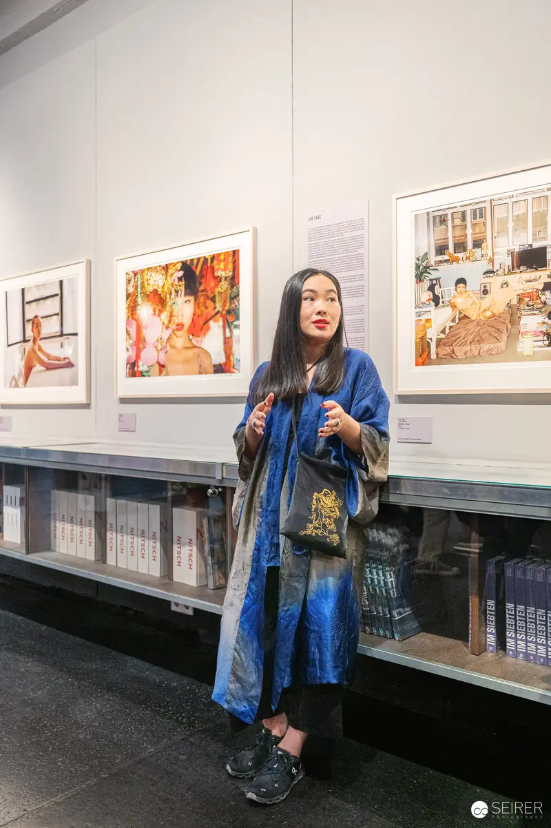 Woman in Blue Coat Viewing Artwork at Gallery Exhibition