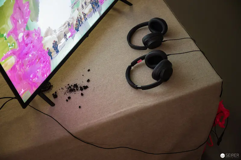Black Headphones Beside Colorful Monitor Displaying Vibrant Pink Scene