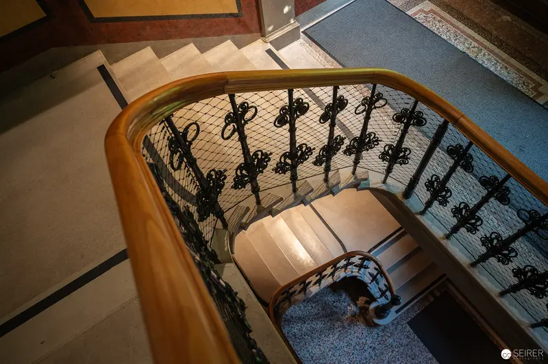 Elegant Wooden Staircase with Ornate Wrought Iron Railings in Historic Building