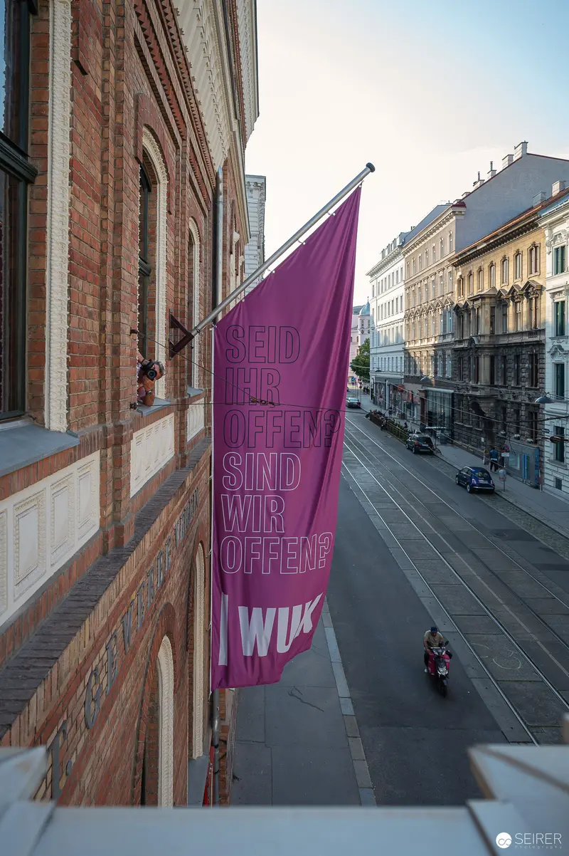 Purple WUK Workshop Flag Hanging on Historic Vienna Streetscape