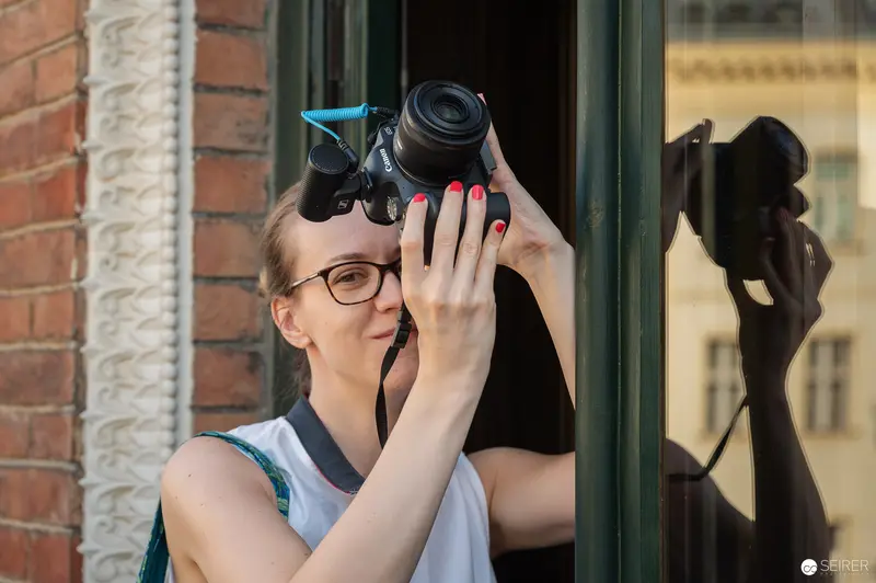Photographer Capturing Urban Scene with Digital Camera and Red Nail Polish