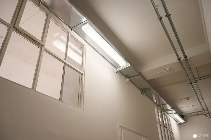 Industrial Interior with Skylights and Exposed Piping at WUK Workshop Space