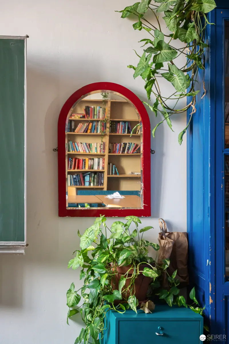 Arched Red-Framed Bookshelf with Lush Green Plants by Blue Wall