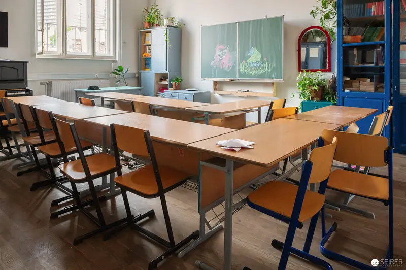 Empty Classroom with Wooden Desks and Green Chalkboard in School Setting