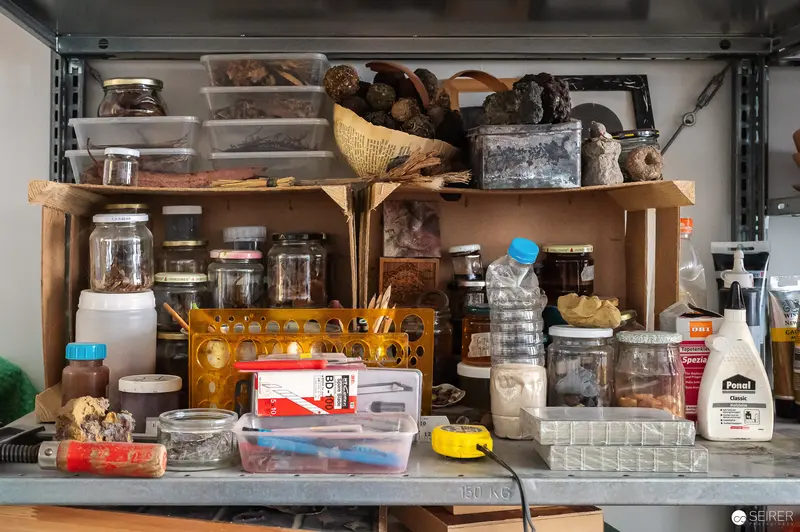 Cluttered Workshop Shelf with Glass Jars, Storage Containers, and Miscellaneous Materials