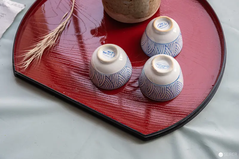 Three Traditional Blue-and-White Japanese Tea Cups on Red Lacquered Tray