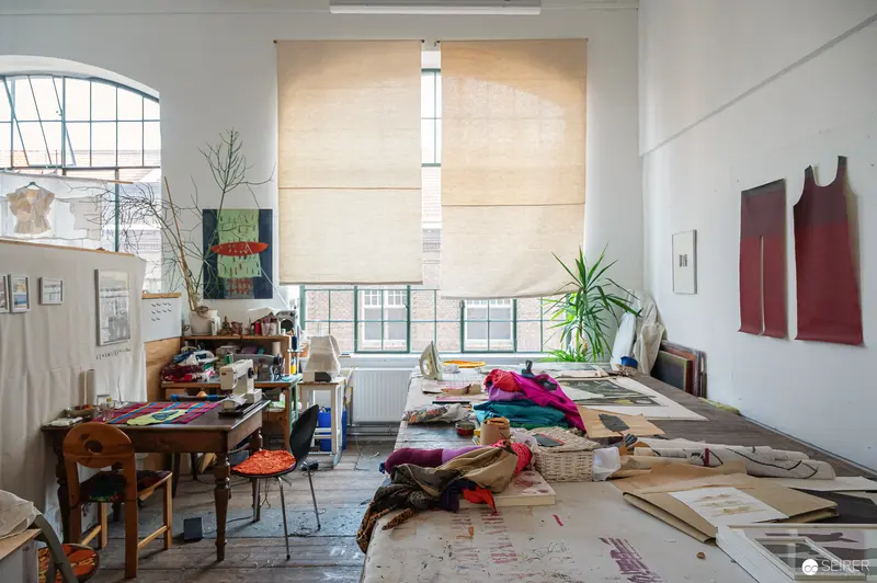 Cluttered Art Studio Interior with Textile Works and Scattered Materials