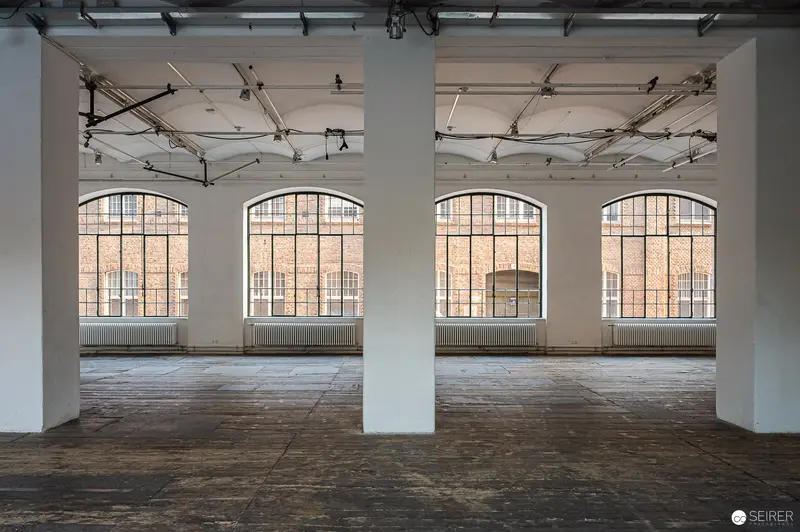 Empty Industrial Loft Interior with Large Arched Windows and Exposed Ceiling Structure