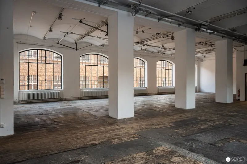 Empty Industrial Space with Arched Windows and Wooden Floors in Renovated Building