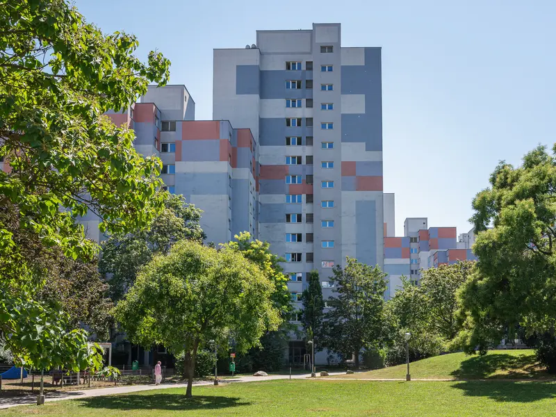 Modern High-Rise Apartment Complex Surrounded by Lush Green Trees in Urban Setting