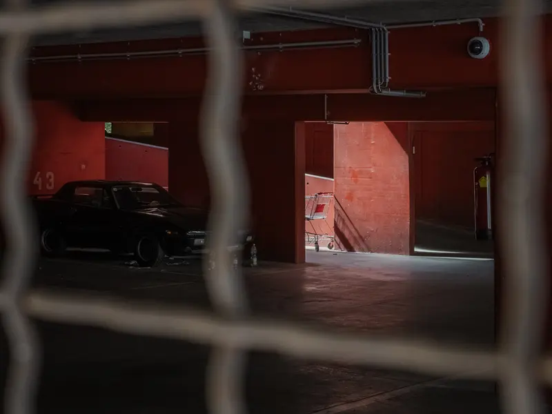 Shadowy Parking Garage Interior Viewed Through Wire Mesh Fence