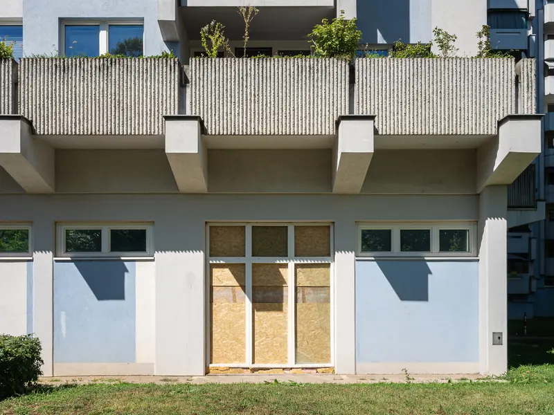 Modernist Apartment Building with Boarded-Up Ground Floor in Urban Setting