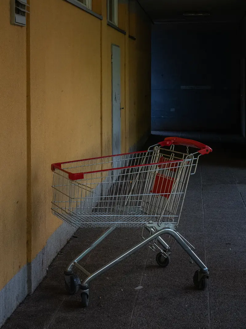 Abandoned Shopping Cart in Empty Hallway with Yellow Wall and Blue Shadow