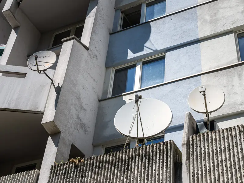 White Satellite Dishes on Modernist Concrete Apartment Building Facade
